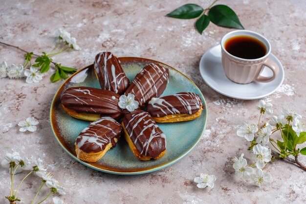 Eclairs ou profiteroles au chocolat noir et chocolat blanc avec de la crème anglaise à l'intérieur, dessert français traditionnel.vue d'en haut.