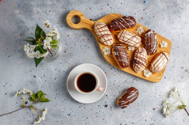 Eclairs ou profiteroles au chocolat noir et chocolat blanc avec de la crème anglaise à l'intérieur, dessert français traditionnel.vue d'en haut.