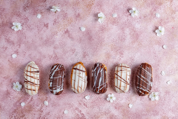 Eclairs ou profiteroles au chocolat noir et chocolat blanc avec de la crème anglaise à l'intérieur, dessert français traditionnel.vue d'en haut.