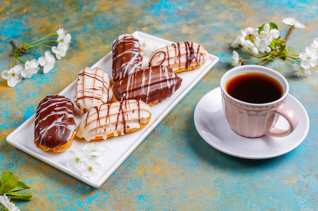 Eclairs ou profiteroles au chocolat noir et chocolat blanc avec crème pâtissière à l'intérieur, dessert français traditionnel.