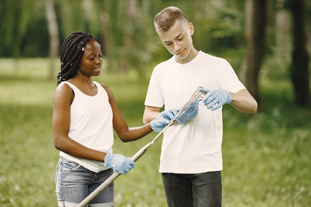 Les éco-activistes se préparent au travail. la fille noire tient des râteaux, le garçon l'aide à vérifier l'équipement.