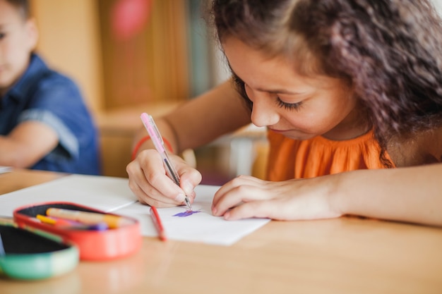 Photo gratuite Écolière assise au dessin de table