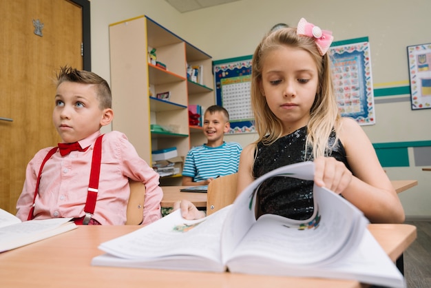 Photo gratuite Écolière assise à la lecture des pages