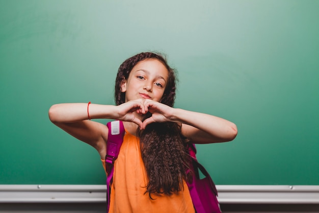 Photo gratuite Écolière brune qui gesticule le coeur