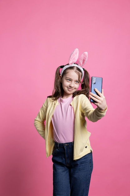 Photo gratuite une écolière mignonne qui prend des photos avec son téléphone portable en studio.