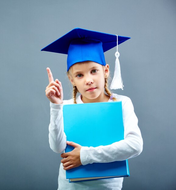 écolière sérieux avec graduation cap bleu