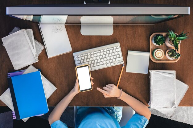 Photo gratuite une écolière avec un smartphone est assise devant un ordinateur et étudie en ligne