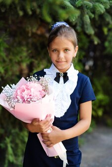 Écolière souriante heureuse avec les fleurs fraîches