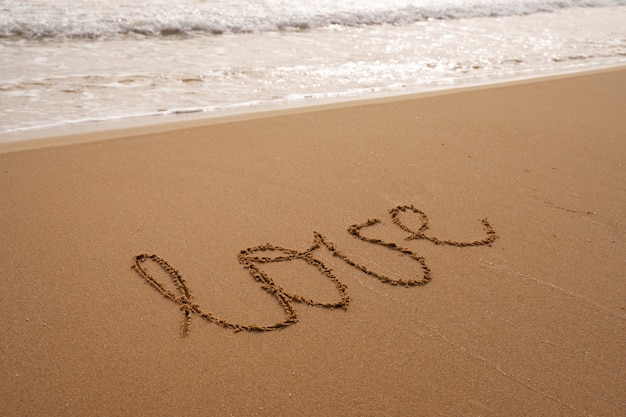 Photo gratuite Écrire des mots dans le sable