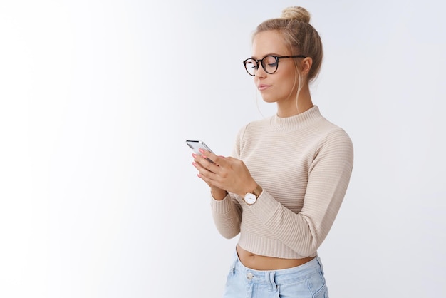 éditeur de magazine femme vérifiant le courrier dans un smartphone portant des lunettes à la mode à l'écran de téléphone mobile souriant fier et heureux posant heureux sur blanc