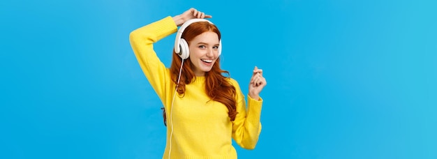 Photo gratuite effronté et joyeux heureux souriant rousse extatique femme s'amusant écouter de la musique et lever les mains