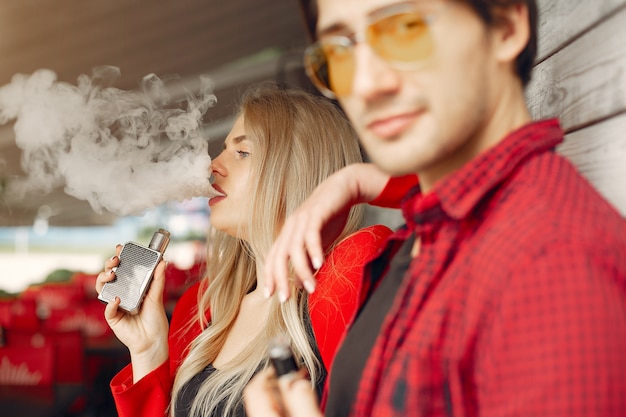 Photo gratuite Élégant jeune couple avec vape dans une ville