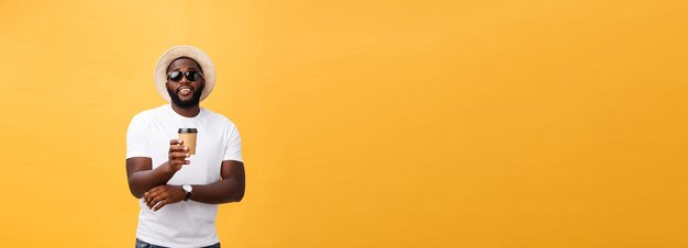 Élégant jeune homme afro-américain tenant une tasse de café à emporter isolé sur fond jaune