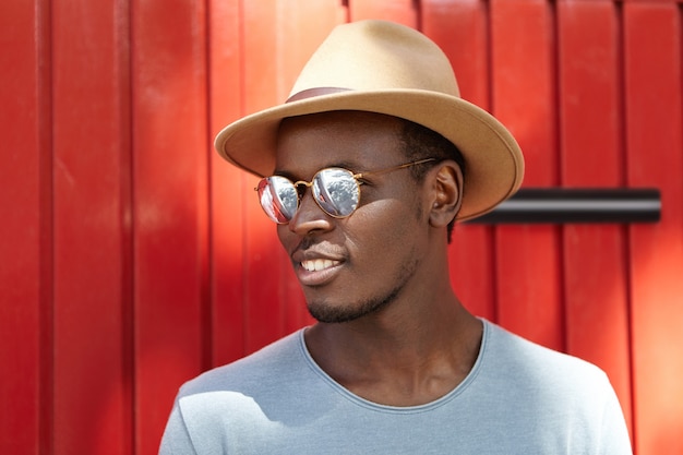 Photo gratuite Élégant jeune homme portant chapeau et lunettes de soleil