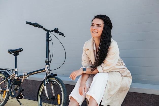 Photo gratuite Élégante femme adulte posant avec vélo écologique