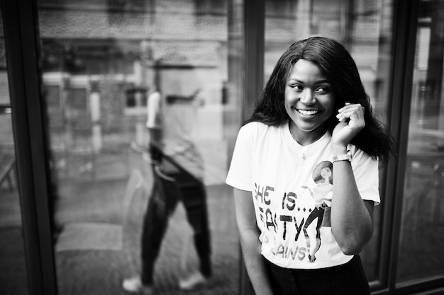 Photo gratuite Élégante femme afro-américaine en t-shirt imprimé posé en plein air contre la fenêtre
