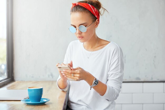 Photo gratuite Élégante femme portant un bandana assis dans un café