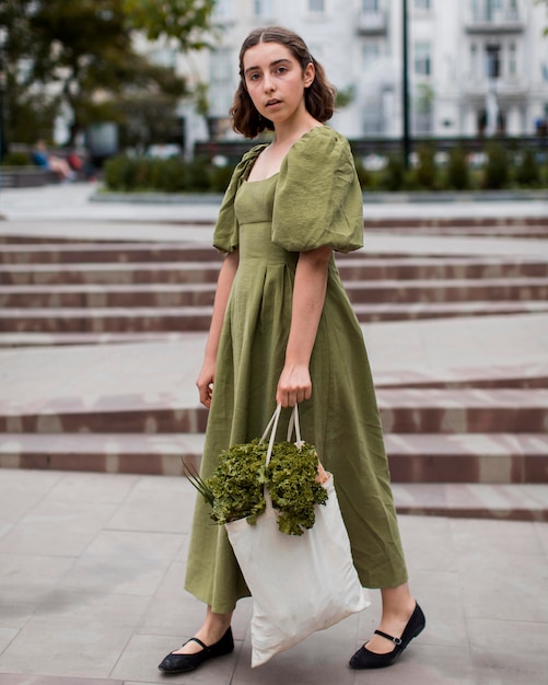 Photo gratuite Élégante jeune femme transportant un sac d'épicerie