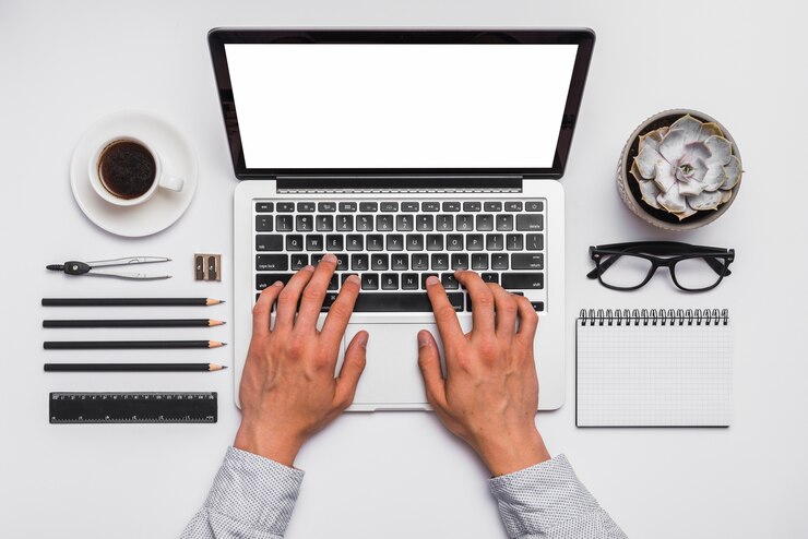 Photo gratuit elevé de la main d&#39;une personne travaillant sur un ordinateur portable au bureau
