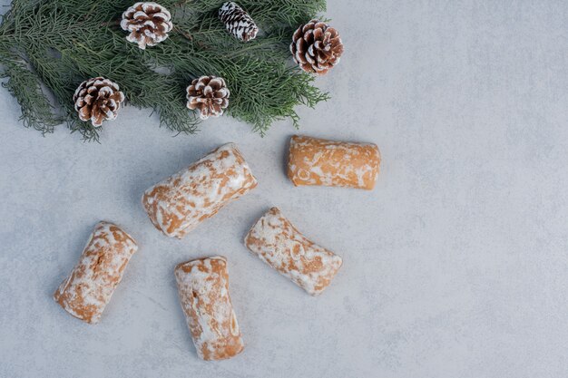 Emballage de biscuits à côté de la branche de pin et des cônes sur la surface en marbre