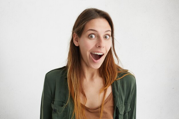 Embarrassée jeune belle femme aux cheveux teints à la recherche avec la bouche ouverte et les yeux surpris isolés.