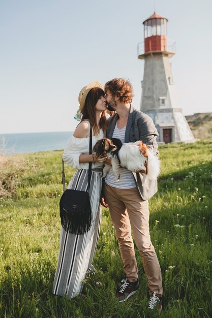 Photo gratuite embrasser un couple hipster élégant amoureux marchant avec un chien dans la campagne