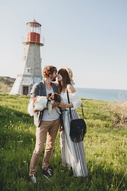 Embrasser un couple hipster élégant amoureux marcher avec un chien dans la campagne, mode boho de style été, romantique