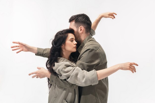 Embrasser. Couple à la mode à la mode isolé sur le mur du studio blanc.