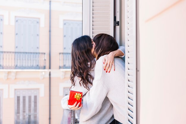 Embrasser les femmes aimantes avec présent sur le balcon