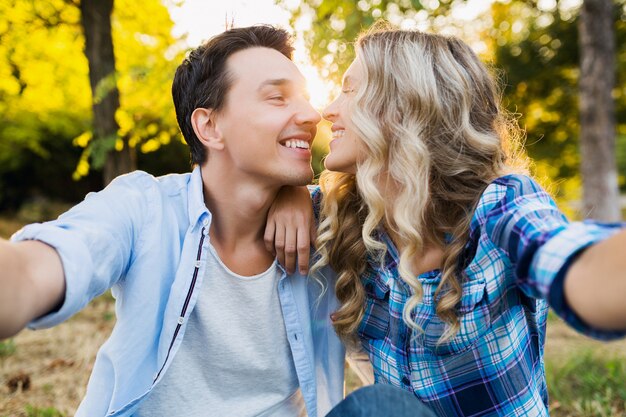 Embrasser le jeune couple élégant assis dans le parc, homme et femme famille heureuse ensemble