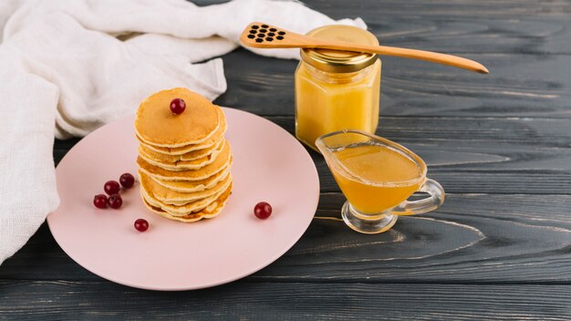 Empilé de crêpes et de baies de cassis rouge avec du lait caillé au citron sur fond en bois