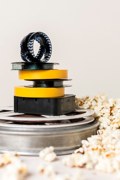 Photo gratuite empilement de bobines de film avec bande de film près du maïs soufflé sur fond blanc