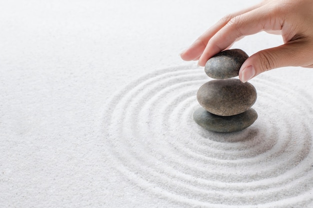 Empiler des pierres zen à la main sur le fond de bien-être du sable