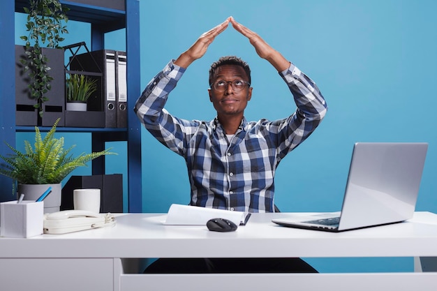 Employé d'une agence d'assurance faisant un geste de toit avec les bras tout en se sentant en sécurité à l'intérieur. Homme d'affaires de l'entreprise annonçant le symbole de sécurité tout en souhaitant la protection de la maison.