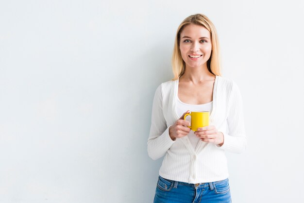 Employé blonde tenant une tasse sur fond blanc