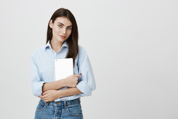 Employé de bureau féminin attrayant tenant une tablette numérique et souriant
