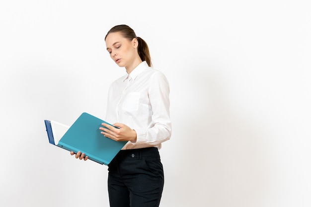 Employé de bureau féminin en chemisier blanc tenant des documents sur le plancher blanc femme document travail de fichier de bureau de travailleur