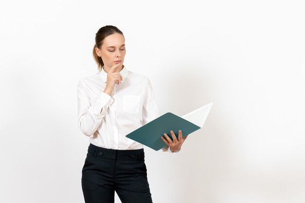 Employé de bureau féminin en chemisier blanc tenant et lisant le fichier bleu sur blanc