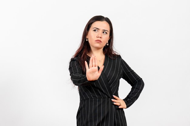 Employé de bureau féminin en costume noir strict montrant un panneau d'arrêt sur blanc