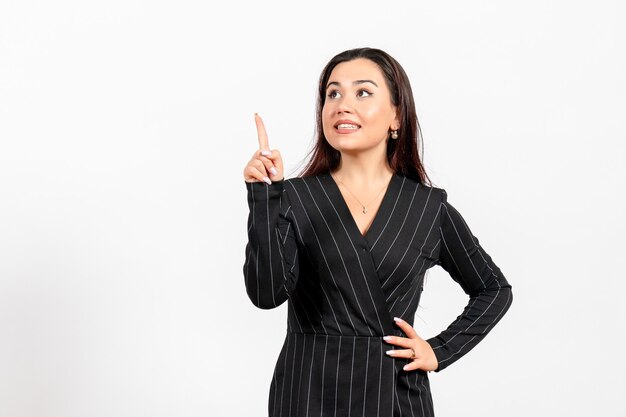 Employé de bureau féminin en costume noir strict posant sur blanc