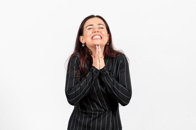 Employé de bureau féminin en costume noir strict posant sur blanc