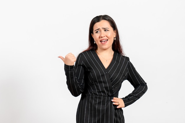 Employé de bureau féminin en costume noir strict posant sur blanc