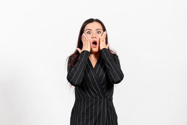 Employé de bureau féminin en costume noir strict posant avec une expression choquée sur blanc