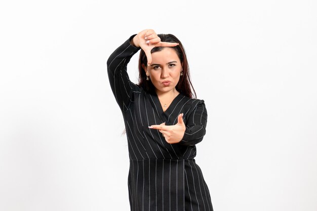 Employé de bureau féminin en costume noir strict posant iin photo prise de manière sur blanc