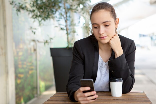 Employé de bureau féminin pensif testant une nouvelle application mobile