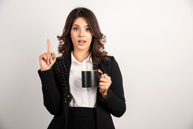 Employé de bureau féminin pointant à l'envers tout en tenant le thé