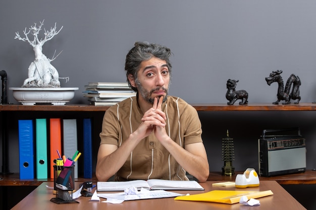 Photo gratuite employé de bureau vue de face assis à son bureau et pensant