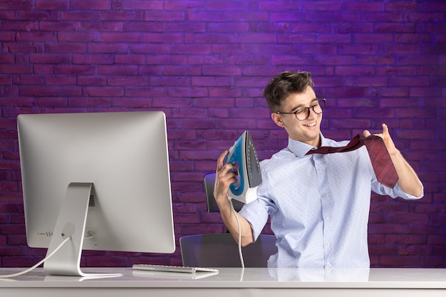 Photo gratuite employé de bureau vue de face derrière le bureau avec fer à repasser