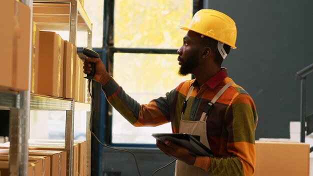 Employé de dépôt scannant le stock de fret avec un scanner de magasin de détail, vérifiant l'expédition de la commande avec une tablette. Employé d'entrepôt se préparant à la distribution, travaillant dans l'industrie manufacturière. Prise de vue à main levée.