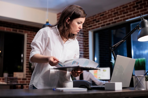 Employé de l'entreprise de marketing dans l'espace de travail de bureau avec presse-papiers de documentation examinant les tableaux de bord. Directeur exécutif analysant les données financières et l'état du projet de démarrage.